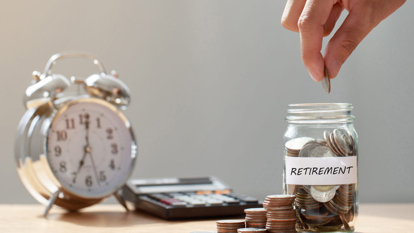 Hand putting coins into jar to save for retirement fund